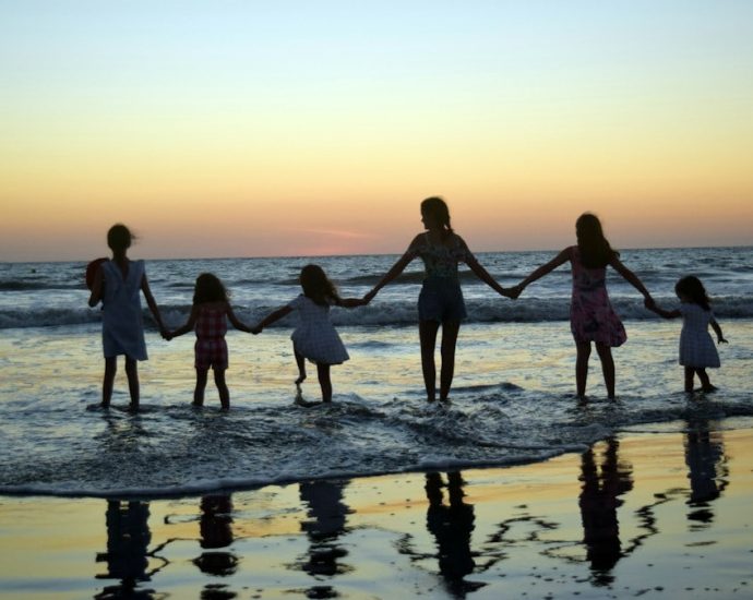 a family holding hands on the beach at sunset
