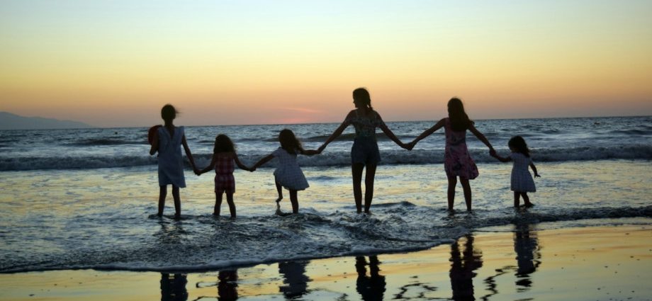 a family holding hands on the beach at sunset