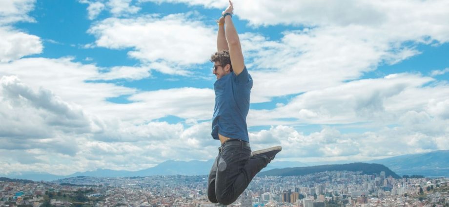 woman in blue tank top and blue denim jeans standing on top of building during daytime
